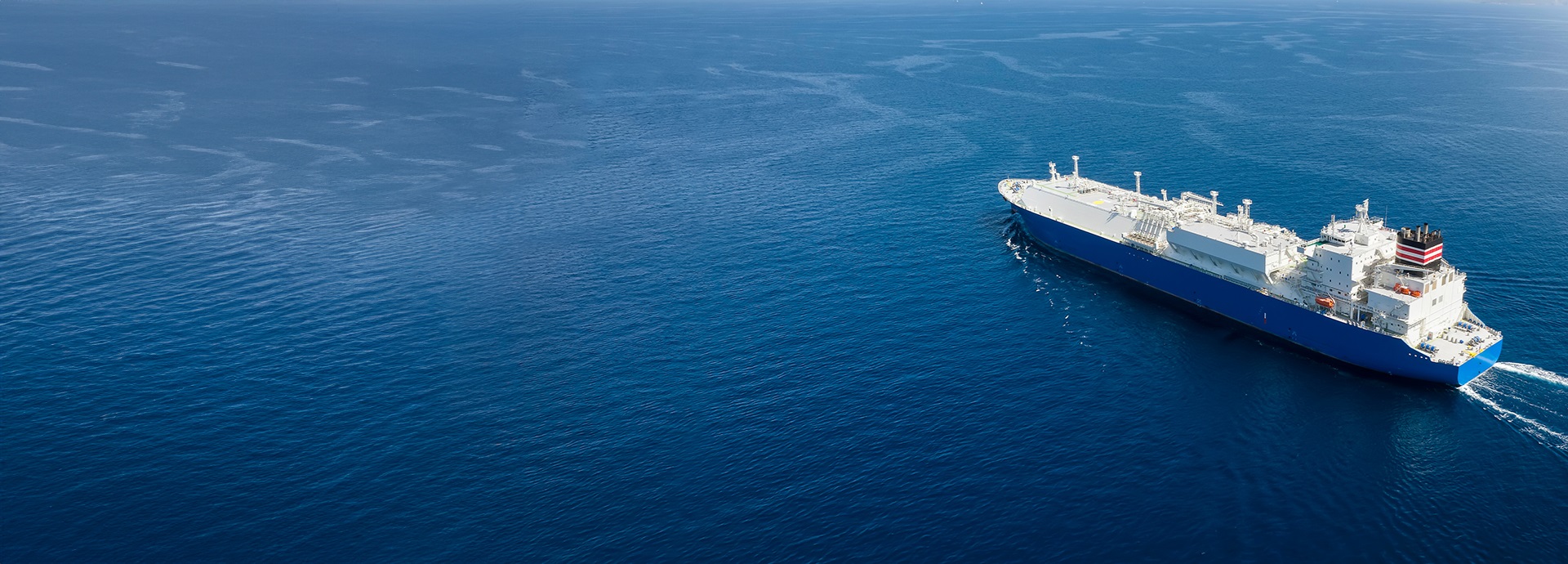 Aerial view of a large LNG tanker ship traveling over calm blue ocean